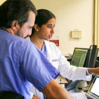 Dr. Megha Prasad engaging in a discussion with Dr. Babak Hassid while examining a cardiac image on a computer monitor